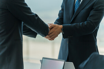 企業のオフィス・会議室で握手をして契約を結ぶビジネスマン
