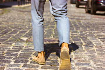 A man in brown suede shoes is walking down the old city street. A businessman, traveller man walks...