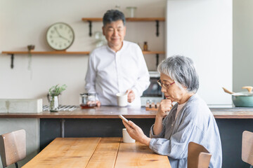 Fototapeta premium 家でスマートフォン・スマホのアプリを使う高齢者女性と男性（困る・悩む・詐欺・トラブル） 