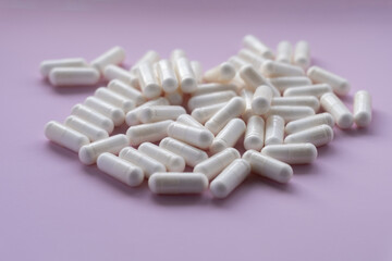 White capsules on a pink background. Dietary supplement in capsules on a pink background.