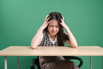 Frustrated woman feeling tired or worried about problems at the table isolated on green background