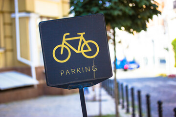 A black bicycle sign with a picture of yellow bike and text parking. Convenient infrastructure of...