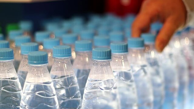 At Supermarket. Bottles with Water and Male hand takes one from store shelf. Healthy lifestyle concept