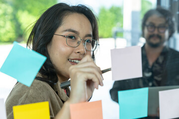 Fototapeta premium The businesswoman is writing down ideas on a notepad stuck to the office glass window
