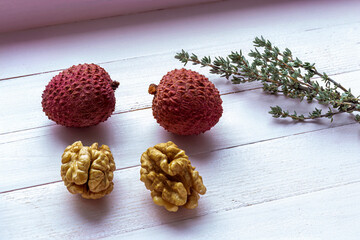 Lychees, walnut, sprig of thyme for fragrant tea. Soft pink wooden background. Delicious and...