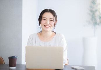 パソコンをしながらカメラ目線の笑顔の若いかわいい女性　正面