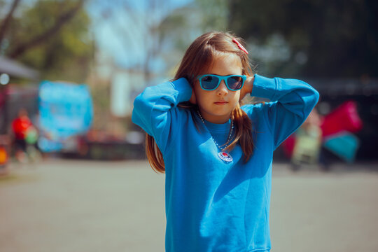 Child Covering her Ears at a Loud Fun Fair Music Festival. Unhappy annoyed little girl finding the funfair too noisy 
