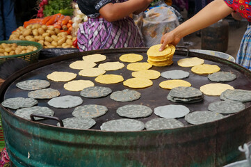 A lady is making tortillas at a market in Central America.