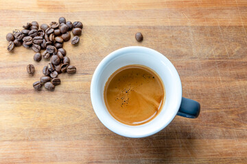 A double shot of espresso set on a wooden board with freshly roasted coffee beans.