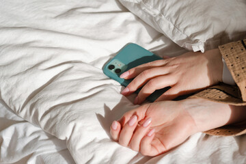 Hand holding smartphone on bed
