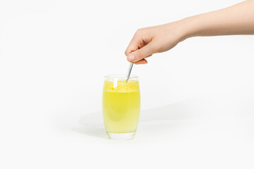 Pouring vitamins (nutritional supplements) into a cup and stirring, against a white background