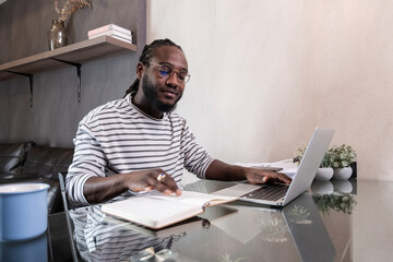 Young African American businessman spends his weekend working from home using his laptop in the living room.