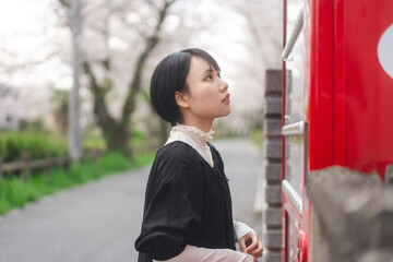 Asian woman consumer using japanese vending machine sakura pack backgroud in Tokyo, Japan
