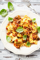 Ravioli with mushrooms and fresh basil. Bright wooden background. Close up.	