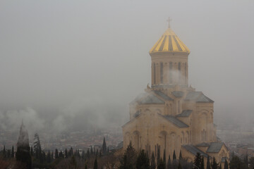 Tsminda Sameba in foggy weather in morning. Golden dome. View of Georgian Orthodox Church. Holy...