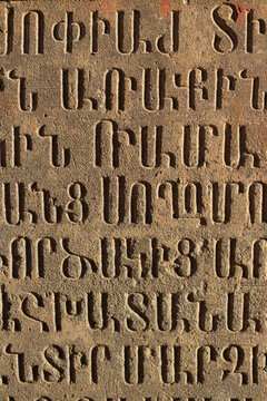 House wall. Stone concrete tablet with set of Armenian letters. Pattern from alphabet of Armenia. Elm. Text. Concept of archaeology, antiquity, history, study, learning, education, reading, travel