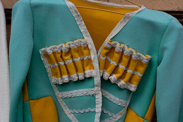 Close up of fragment of yellow-green national folk festive Georgian male costume called chokha, cherkeska with containers for gunpowder called gazyr. Bandolier. Concept of fashion, authenticity, dress