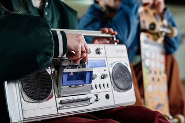 Closeup of unrecognizable girl inserting audio cassette into retro boombox to listen to music, copy...