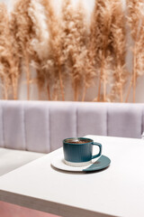 Cup of hot black coffee on white table on natural plant decor background
