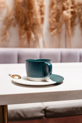 Ceramic cup of hot Americano on white table. Concept of hot drinks on light background with dried flowers