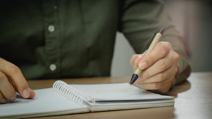 businessman working at work table,home office desk background, checklist writing planning investigate enthusiastic concept. Male hand taking notes on the notepad.	