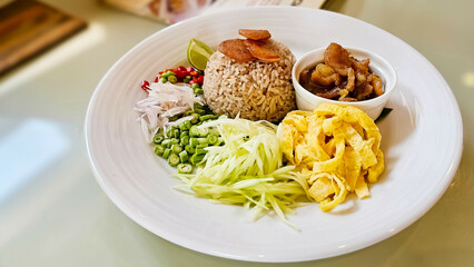 Thai Food Khao Kluk Kapi. Shrimp Paste Fried Rice served with various sides or toppings, Sliced omelette, Sweet pork, Green mangoes And vegetables. Thai restaurant. Thai Cuisine. - obrazy, fototapety, plakaty