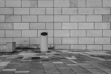 A trash can in front of a sandstone facade, minimalist, urban trash can, black and white photo