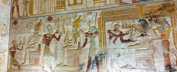 Pharoah Seti I offering prayers to guardian diety of the underworld, Osiris in this painted wall reliefs in the Temple of Seti built in 13th century BC by the Pharoah Seti I near Abydos,Egypt