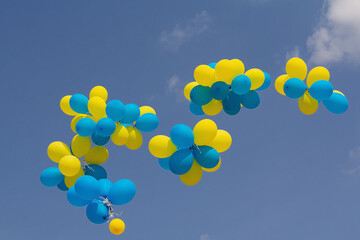 Yellow and blue balloons fly in the bright blue sky on a sunny day