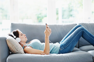 Girl, headphones and phone on sofa in house for music, relax and self care while on study break....