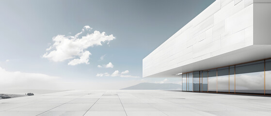 A large white building with a glass facade sits on a white tiled roof. The building is surrounded by a large empty space, giving it a sense of openness and grandeur