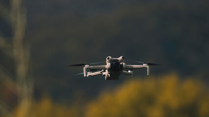 Drone with digital camera flying in the sky over the field.