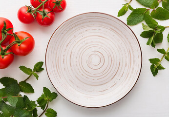 Empty ceramic plates on white wood table with kitchen Peppermint and red tomato - Powered by Adobe