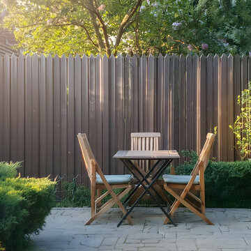 chair and table.a backyard scene with a table and chairs arranged elegantly by a wooden fence. The composition should exude a sense of peace and serenity, with the surrounding greenery and subtle sunl