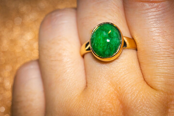 Gold ring with green stone. Fashion golden ring with green stone, close up background.