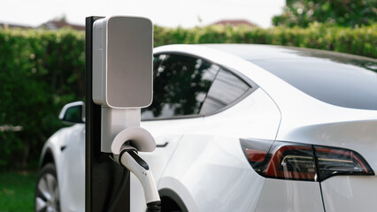 Closeup EV charger plug handle attached to electric vehicle port, recharging battery from charging...
