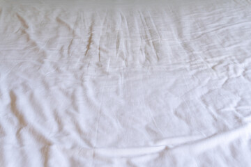 Crumpled or wrinkled white bedding sheet background texture taken with soft natural light used for clothing background texture