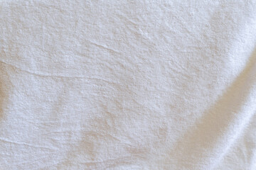 Crumpled or wrinkled white towel background texture taken with soft natural light used for clothing background texture