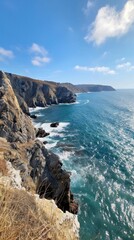 A rugged coastline stretching into the distance, waves crashing against dramatic cliffs, panoramic view