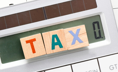 TAX word arranged with wooden letters on the calculator screen.