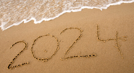 2024 written by hand on the beach. Start of new year 2024 concept.
