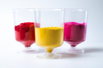 Multicolored holi powder in a glass isolated on white background.