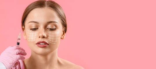 Young woman receiving filler injection in face against beige background