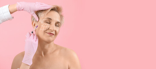 Young woman receiving filler injection in face against beige background