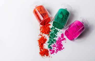Tricolor Holi powder in plastic containers on white background.