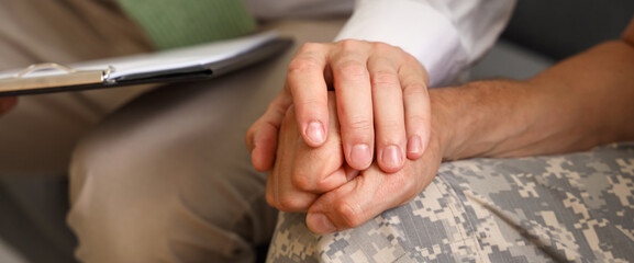 Male psychologist working with mature soldier in office, closeup
