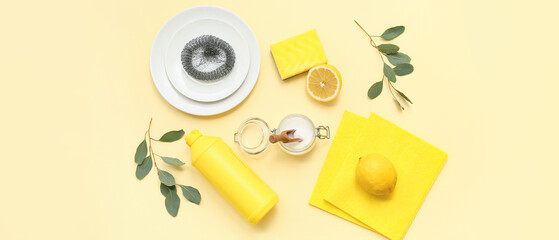 Soda with lemon, bottle of detergent and cleaning supplies on light yellow background