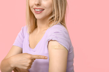 Young woman with medical patch on arm against pink background. Vaccination concept