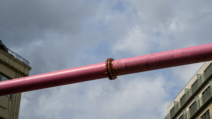 Two houses facing each other in the foreground connected by a pink pipe