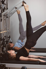 Young women exercising in a gym on pilates machines.